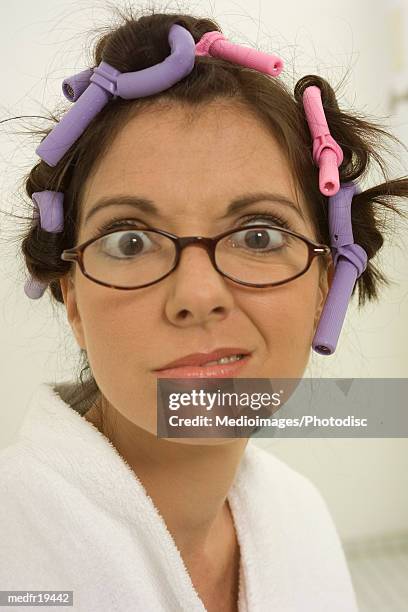 one mid adult woman with hair in curlers making faces - hair curlers stockfoto's en -beelden