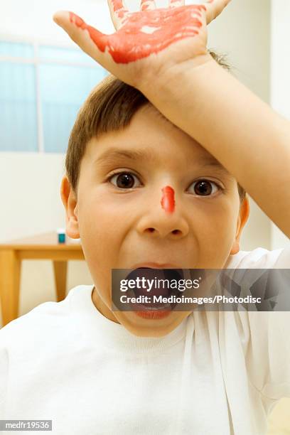 a young boy with his hand painted - hand on head foto e immagini stock