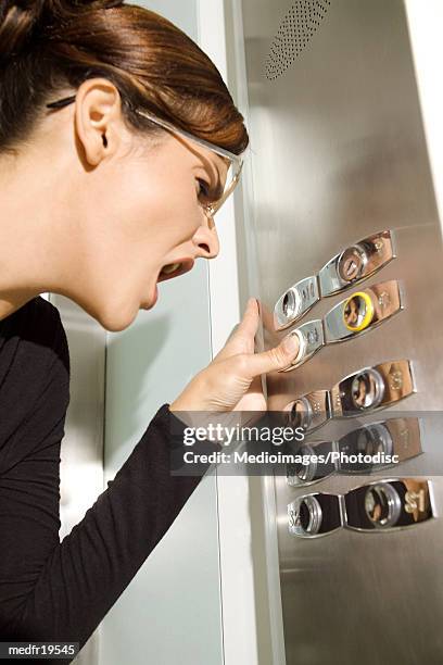 a young woman in elevator pressing buttons - elevator trapped stock pictures, royalty-free photos & images