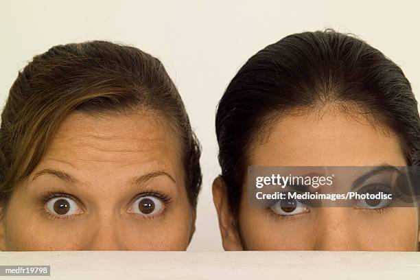 close-up of two women's faces peering over a counter - close up counter ストックフォトと画像