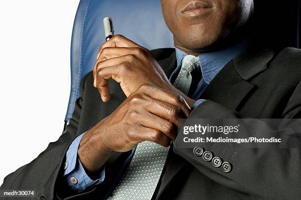 mid section of black businessman sitting in blue high back chair and holding a  pen, close-up, part of - back of chair stock pictures, royalty-free photos & images