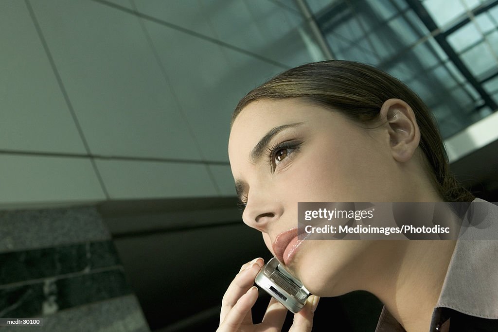 Serious young businesswoman talking on cell phone, close-up