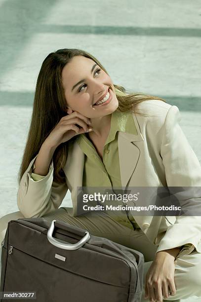 smiling businesswoman resting head on hand and with briefcase in front of her, close-up - hand on head foto e immagini stock