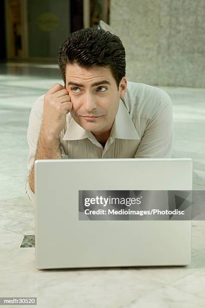 businessman resting head on hand and lying on floor working on laptop - hand on head foto e immagini stock
