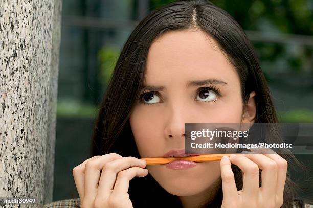 young woman biting a pencil - hair parting stockfoto's en -beelden