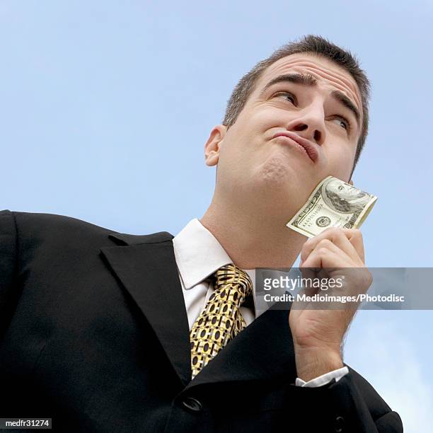 extreme close-up of businessman outdoors holding one hundred dollar bill, low angle view - crew cut stock pictures, royalty-free photos & images