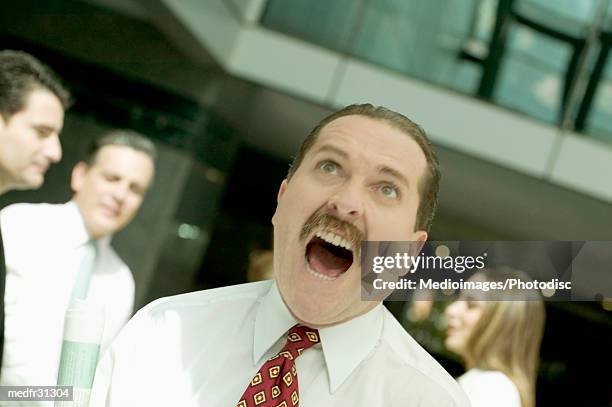 angry businessman yelling outdoors with other business people in the background, close-up, tilt, selective focus - hazel eyes stock pictures, royalty-free photos & images