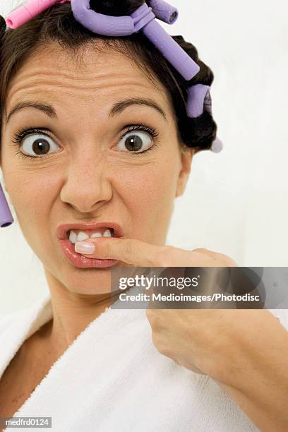 woman with curlers in hair and finger on teeth, extreme close-up - hair curlers stockfoto's en -beelden