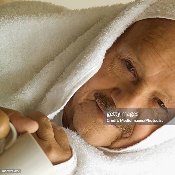 senior man with head wrapped in a towel and holding cup of coffee or tea, close-up - or stock pictures, royalty-free photos & images