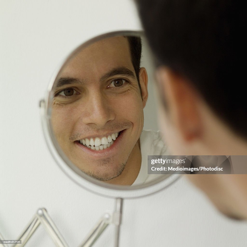 Close-up of a young man smiling in a mirror