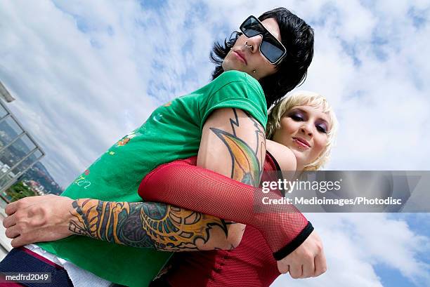 goth couple outside back to back with arms intertwined, low angle view - joined at hip stock pictures, royalty-free photos & images