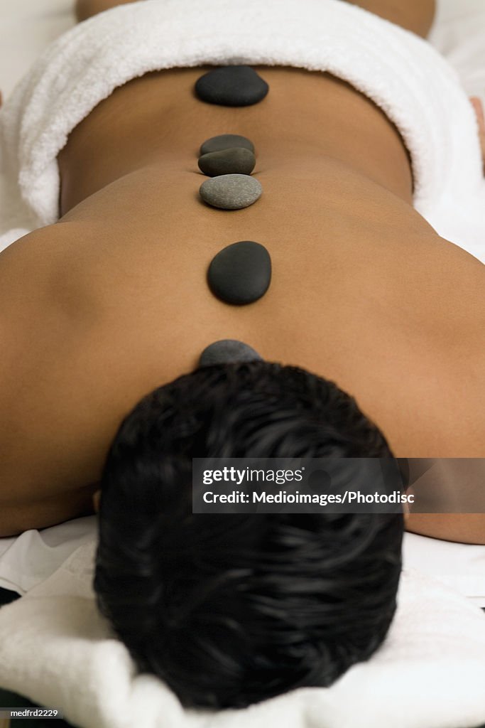 Person lying down with therapeutic stones on the back