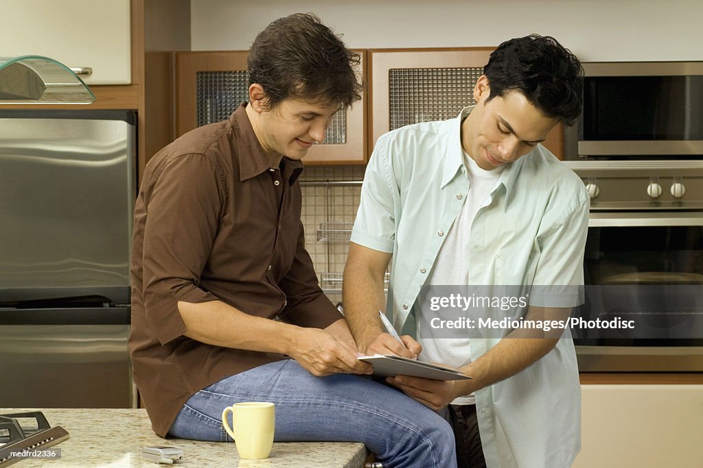 Side profile of two men making notes in a kitchen