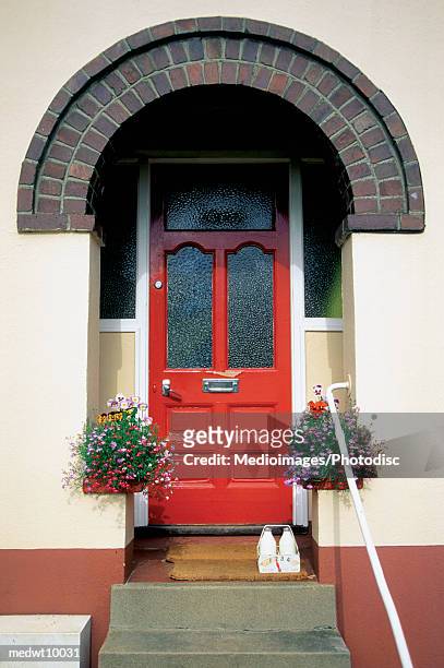 bottles of milk and hanging plants outside house with red door in totnes, england - feng shui house stock pictures, royalty-free photos & images