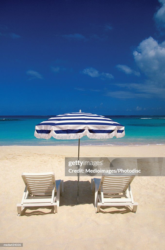 One black and white umbrella and white lounge chairs on Shoal Bay Beach on Anguilla, Caribbean