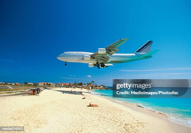 plane coming in for landing on maho bay beach, saint martin, caribbean - saint martin caraibi stock-fotos und bilder