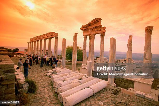tourists at the ruins of the temple of trajan at sunset in pergamon, bergama, aegean region, turkey - pergamon stock-fotos und bilder