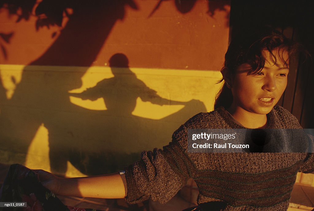 A dancing woman casts a shadow on a brightly-painted wall.