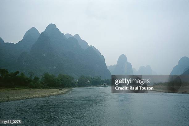 the li river winds through a landscape of towering karst formations. - sudeste da china imagens e fotografias de stock