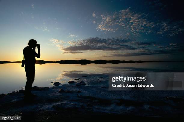 lake gairdner, gawler ranges national park, south australia. silhouetted photographer at twilight on flooded salt lake. - gawler ranges national park stock pictures, royalty-free photos & images