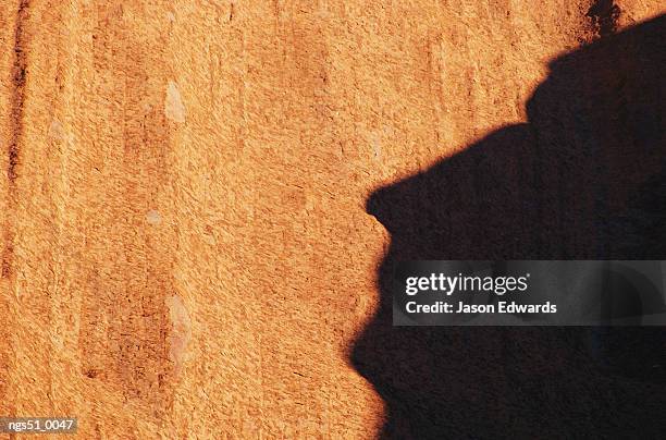 uluru national park, northern territory, australia. a human-like shadow cast by a rock formation onto another large rock. - uluru kata tjuta national park stock pictures, royalty-free photos & images