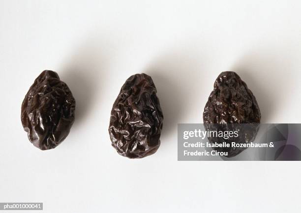three prunes against white background, close-up - dried plum stock pictures, royalty-free photos & images
