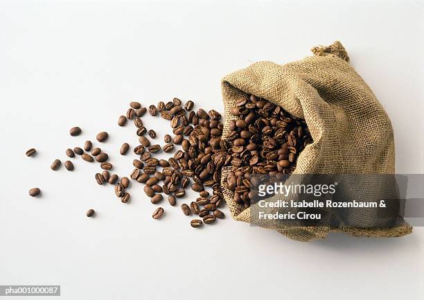 coffee beans in and spilling out of burlap sack - coffee bag stock-fotos und bilder