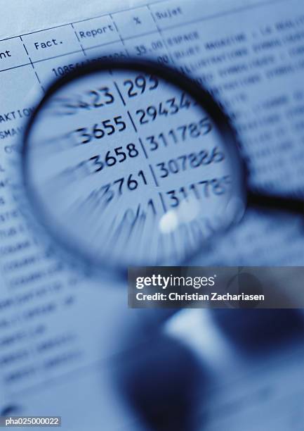 magnifying glass magnifying numbers on document, close-up, blurred - share prices of consumer companies pushes dow jones industrials average sharply higher stockfoto's en -beelden
