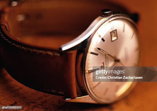 wristwatch with white face and leather band, wood background, close-up - orologio di lusso foto e immagini stock