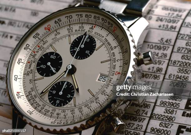 wristwatch on top of stock report, extreme close-up - luxury watch stock pictures, royalty-free photos & images