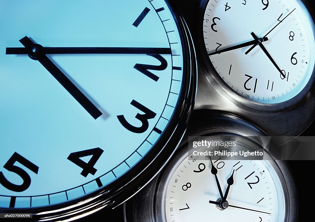 Three clocks, each with hands at a different time, extreme close-up