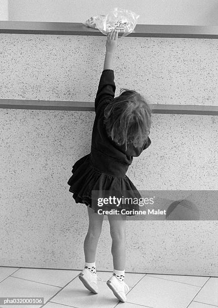 little girl standing on tiptoes, reaching up toward plastic bag on shelf, b&w - small plastic bag stock pictures, royalty-free photos & images