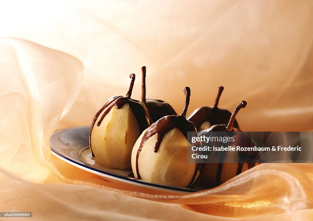 Pears semi-covered with melted chocolate, on plate