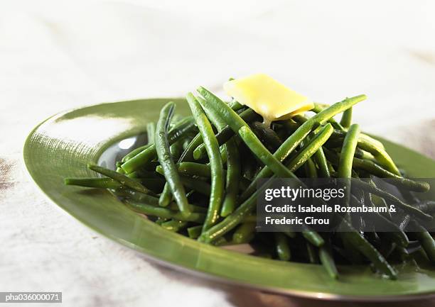 cooked green beans with pat of butter on top, on green plate, close-up - green bean stock pictures, royalty-free photos & images