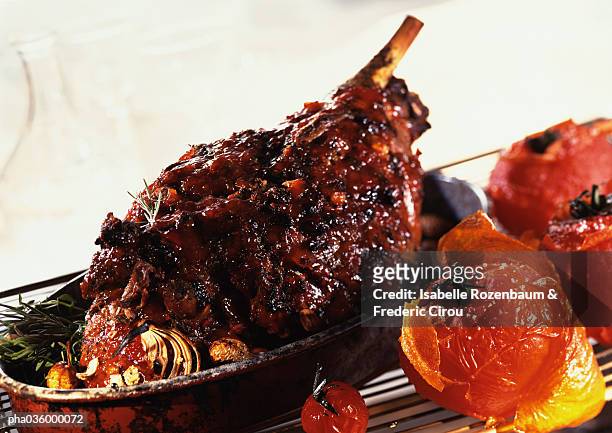 roasted leg of lamb with tomatoes and herbs, in casserole, close-up - leg of lamb stock-fotos und bilder