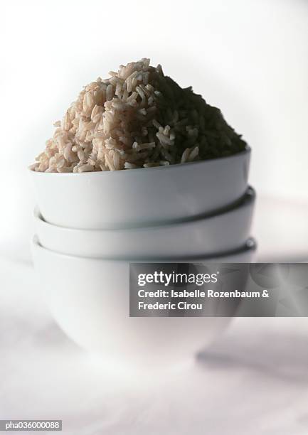 stack of three white bowls, mound of brown rice in top bowl, close-up - macrobiotic diet stock pictures, royalty-free photos & images