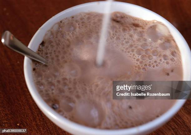 chocolate milk in bowl, with spoon, liquid being poured into bowl, blurred - chocolate milk stock pictures, royalty-free photos & images