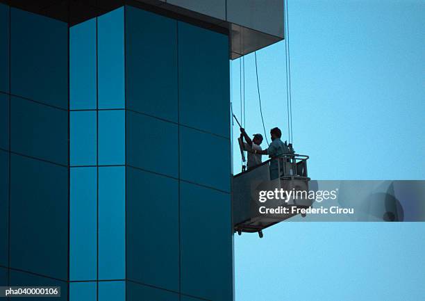 two men cleaning skyscraper's facade - fensterfront stock-fotos und bilder