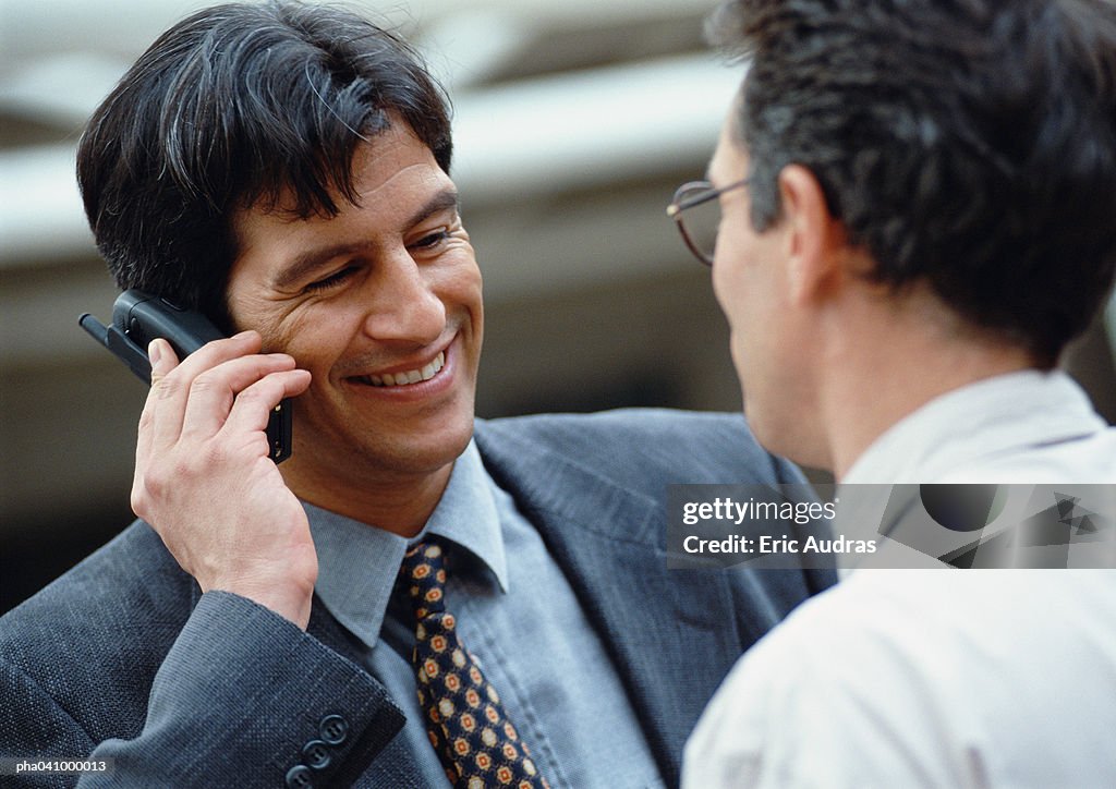 Businessman holding cell phone, smiling