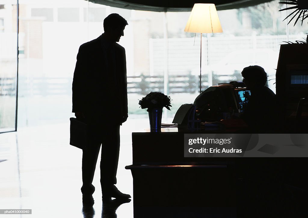 Silhouette of businessman standing in front of desk