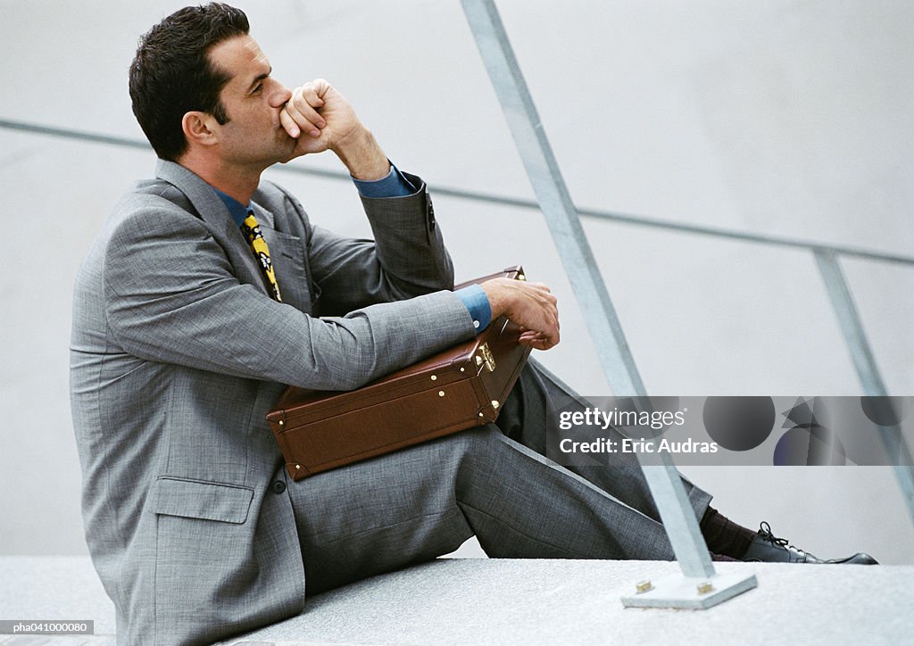 Businessman sitting on stairs, holding briefcase