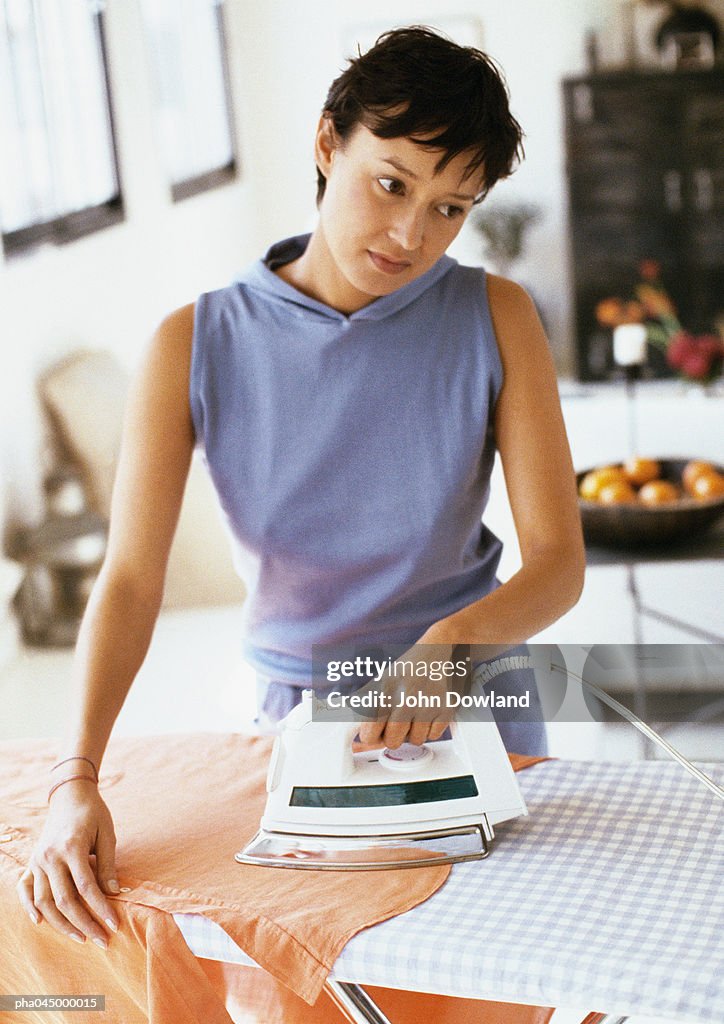 Woman looking away with head tilted ironing clothes, waist up