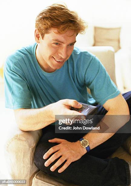 man sitting, holding remote control, close-up - zapping stock pictures, royalty-free photos & images
