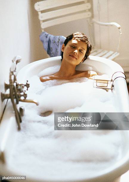 woman taking bubble bath, front view, full length - bubbelbad stockfoto's en -beelden