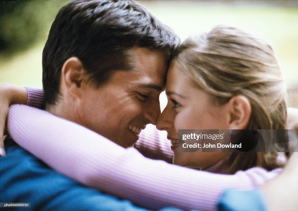 Man and woman smiling, foreheads and noses touching, side view, close-up