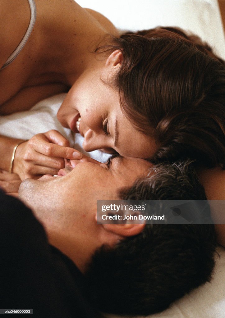Couple lying in bed, face to face, close-up of heads