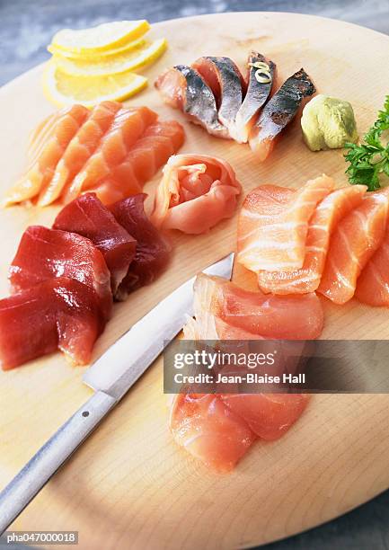 sashimi with wasabi and lemon slices on wooden board - sushis stockfoto's en -beelden