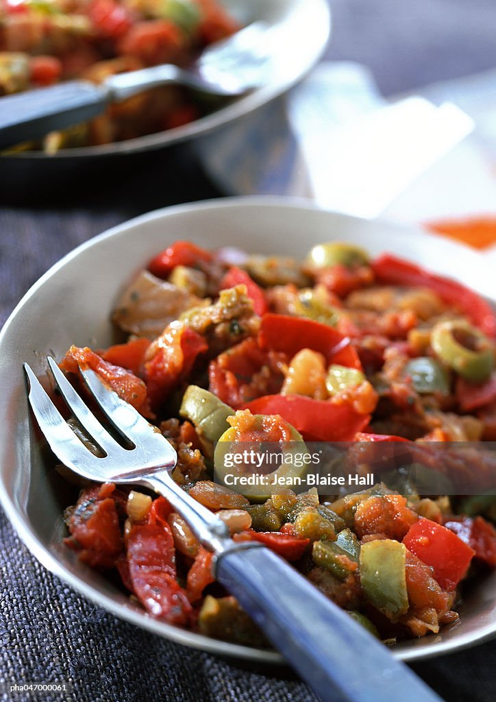 Red pepper and olive dish in bowl with fork, close-up
