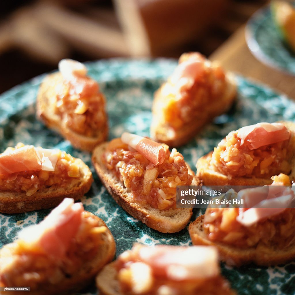 Crackers topped with canteloupe and ham, close-up