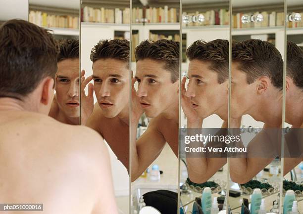 man touching eyebrow, focus on multiple reflections in mirrors - ego perspektive stock-fotos und bilder